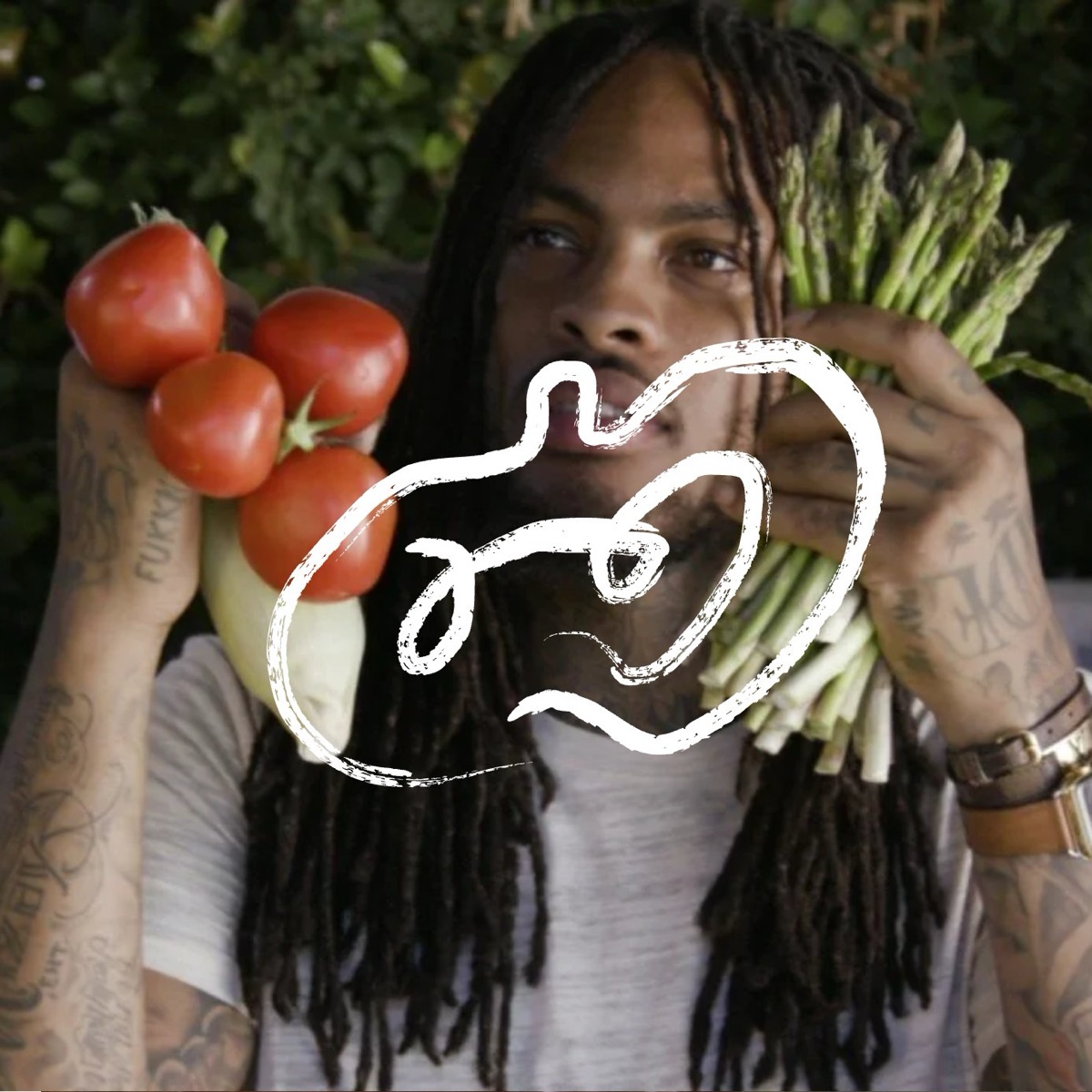 Waka Flocka Flame holding tomatoes and asparagus, with the white apple mark drawn over the photo