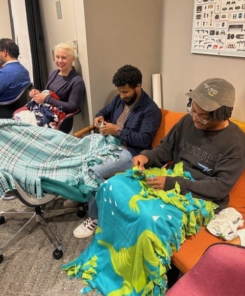 Teammates tying fleece blankets together.
