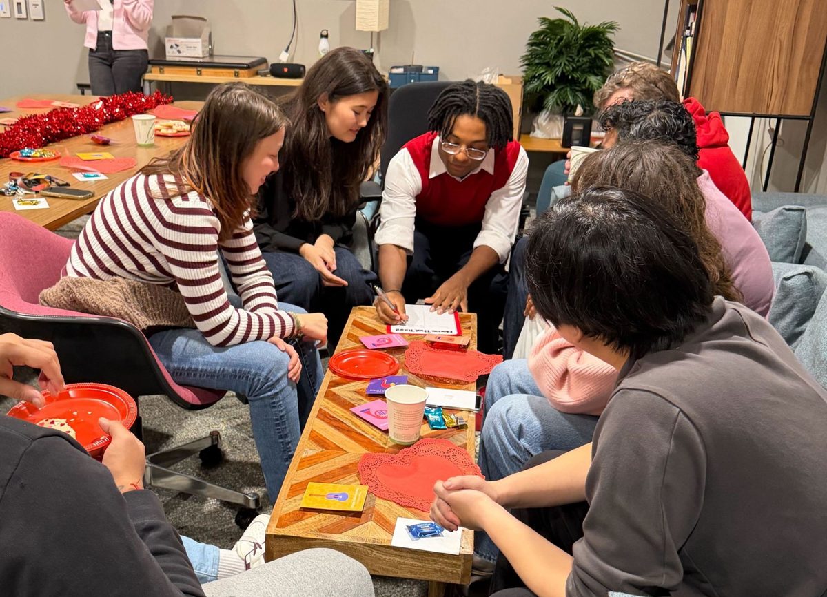 Teammates gathered around a table at a Valentine's Day party, playing a game.